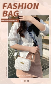 Detail of white quilted crossbody bag with golden emblem and branded wide strap