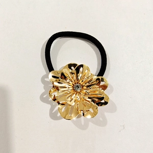 Detail of golden hollow flower hair tie with sparkling rhinestone on elastic band