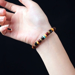 Colorful multi-gemstone wooden bead bracelet with elastic cord on a model's wrist