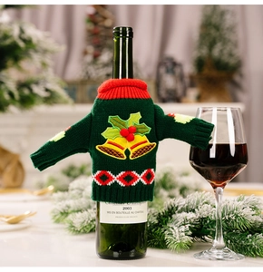Detail of green knitted Christmas wine bottle sweater with bell and berry pattern