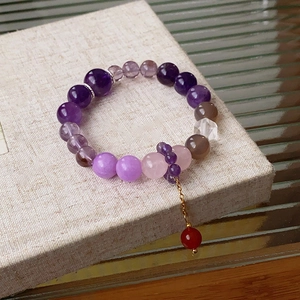 Detail view of colorful fluorite beaded bracelet with gold chain and red pendant charm