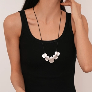 Detail of silver irregular circular pendant necklace on model wearing a black tank top