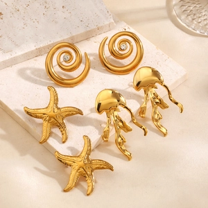 Golden starfish jellyfish and spiral zircon earrings set displayed on white stone and silk