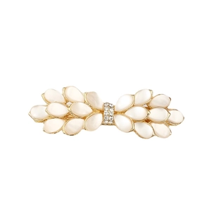 Elegant gold bow hair clip with opal stones and sparkling crystals on white background