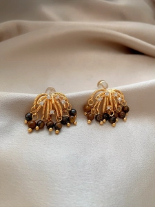 Macro shot of vintage tassel earrings with sparkling zircons and brown tiger eye beads
