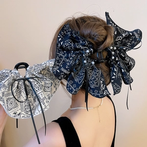 Detail of vintage paisley bow hair claw with elegant pearls and long ribbon tassels