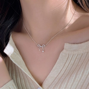 Elegant silver bow pendant necklace with sparkling crystal worn on a female model