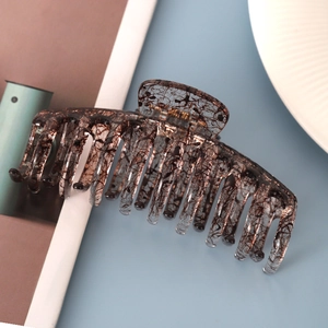 Detail shot of a large marble pattern hair claw clip on a soft blue background