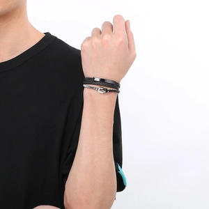 Detail of layered black leather woven bracelet with silver metal chain and magnetic clasp
