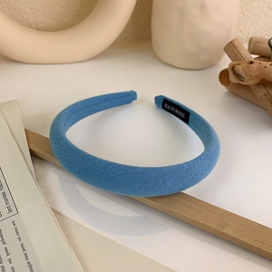 Detail of blue fabric padded headband with handmade label on aesthetic newspaper