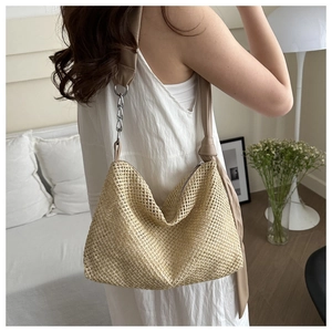 Detail view of woven straw shoulder bag with metallic chain and fabric strap