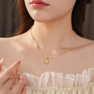 Close-up of golden star pendant necklace with freshwater pearls on elegant model's neck