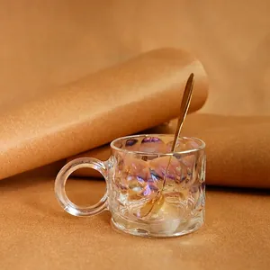 Iridescent hammered glass coffee mug with round handle and gold spoon in home setting