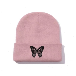 Close-up of pink knit beanie featuring detailed black butterfly embroidery on the cuff