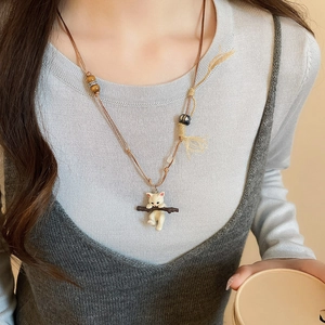 Detail of cute ceramic cat pendant with wooden beads on brown wax cord necklace