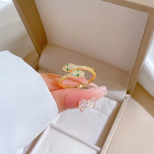 Adjustable gold snake ring featuring green gem eyes and sparkling white crystal stones
