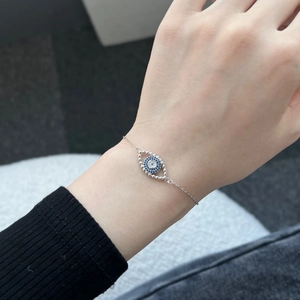 Makroaufnahme des Silberarmbands mit blauem und weißem Zirkonia Auge am Handgelenk