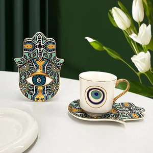 Detail of Turkish evil eye ceramic coffee cup with gold handle and Hamsa hand saucer