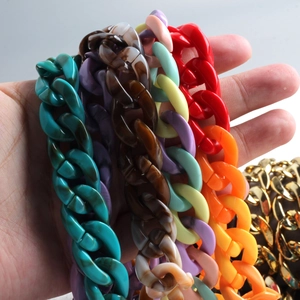 Close-up of colorful chunky acrylic and gold metal phone chains held in hand