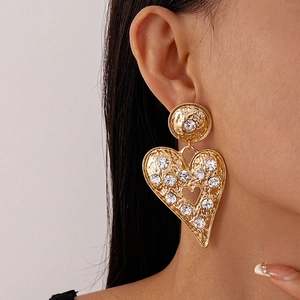Close-up of model wearing gold hammered heart earrings with sparkling rhinestones