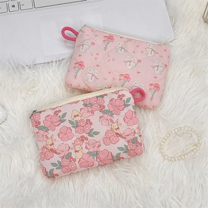 Close-up of pink quilted mini makeup bags with cute floral patterns on white fur background