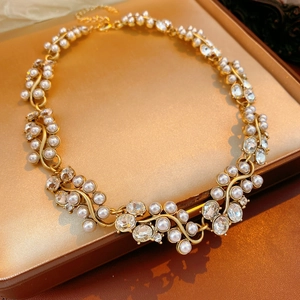 Macro detail of a vintage gold-toned necklace with rhinestones and elegant faux pearls