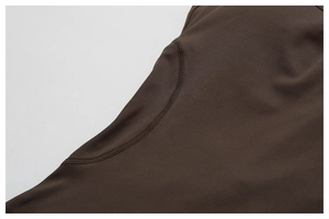 Detail view of double-stitched curved seams on high-stretch brown yoga bodysuit fabric