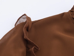 Détail du volant sur robe longue en mousseline marron foncé avec coutures fines