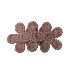 Détail d'une barrette à fleurs brodées marron avec trois motifs floraux délicats
