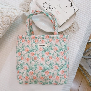 Detailed close-up of quilted floral tote bag with simple wish label on white background