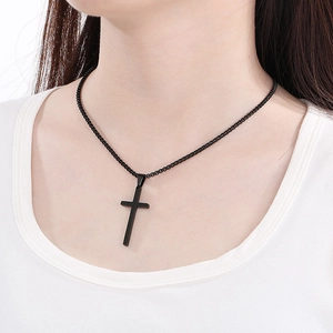 Close-up of a minimalist black stainless steel cross pendant with a matching box chain