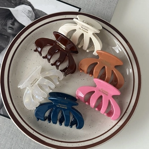 Detailed view of six colorful pumpkin-shaped hair claws arranged in a ceramic plate