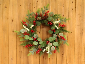 Close-up of Christmas wreath with pine needles, eucalyptus leaves and red berries on wood