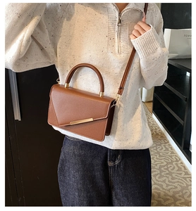 Detailed view of the dark brown lychee grain leather crossbody bag with gold metal clasp