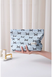 Detailed view of blue cotton makeup bag with black bow patterns and H & R BAG label