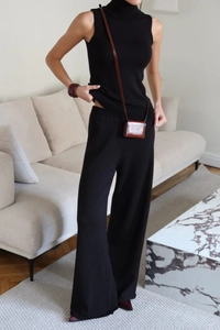 Detail of black knit two-piece set featuring high neck sleeveless top and wide-leg pants