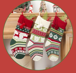Three knitted Christmas stockings with reindeer and snowflake patterns on a fireplace