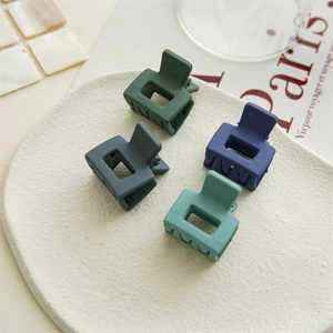 Detailed view of four matte Morandi square hair claws on a decorative white plate