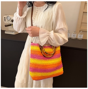 Detail of colorful striped straw tote with bamboo handles and brown shoulder strap