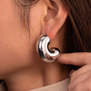 Polished silver stainless steel chunky C-shape hoop earring worn on model profile