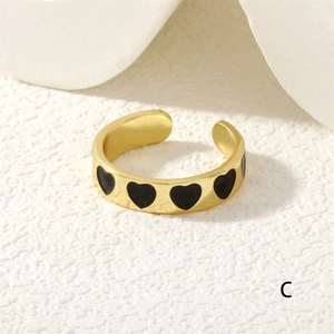 Detail of adjustable gold ring featuring black heart patterns and an open band design