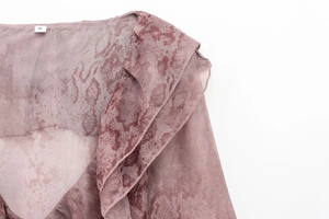 Close-up detail of ruffled collar and shoulder stitching on animal print chiffon shirt