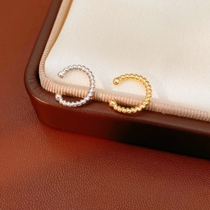 Detail of twisted rope ear cuffs in gold and silver finish on a premium jewelry box