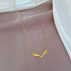 Dettaglio di una collana con ciondolo a corna di cervo dorata su tessuto di seta