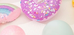 Vue détaillée de bombes de bain macaron colorées en forme de donut et d'arc-en-ciel à paillettes