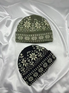 Detail von armeegrünen und schwarzen Strickmützen mit weißem Schneeflocken-Jacquard