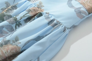 Dettaglio dell'abito floreale azzurro che mostra la trama rosa e la lavorazione a pieghe