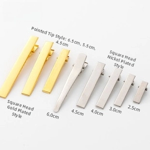 Various sizes of gold and silver metal alligator hair clips displayed on a white background