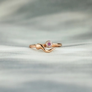 Rose gold s925 silver evil eye ring with pink gemstones on grey fabric background