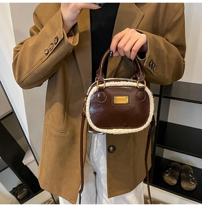 Detail of a brown faux leather handbag with soft white fleece trim and dual top handles